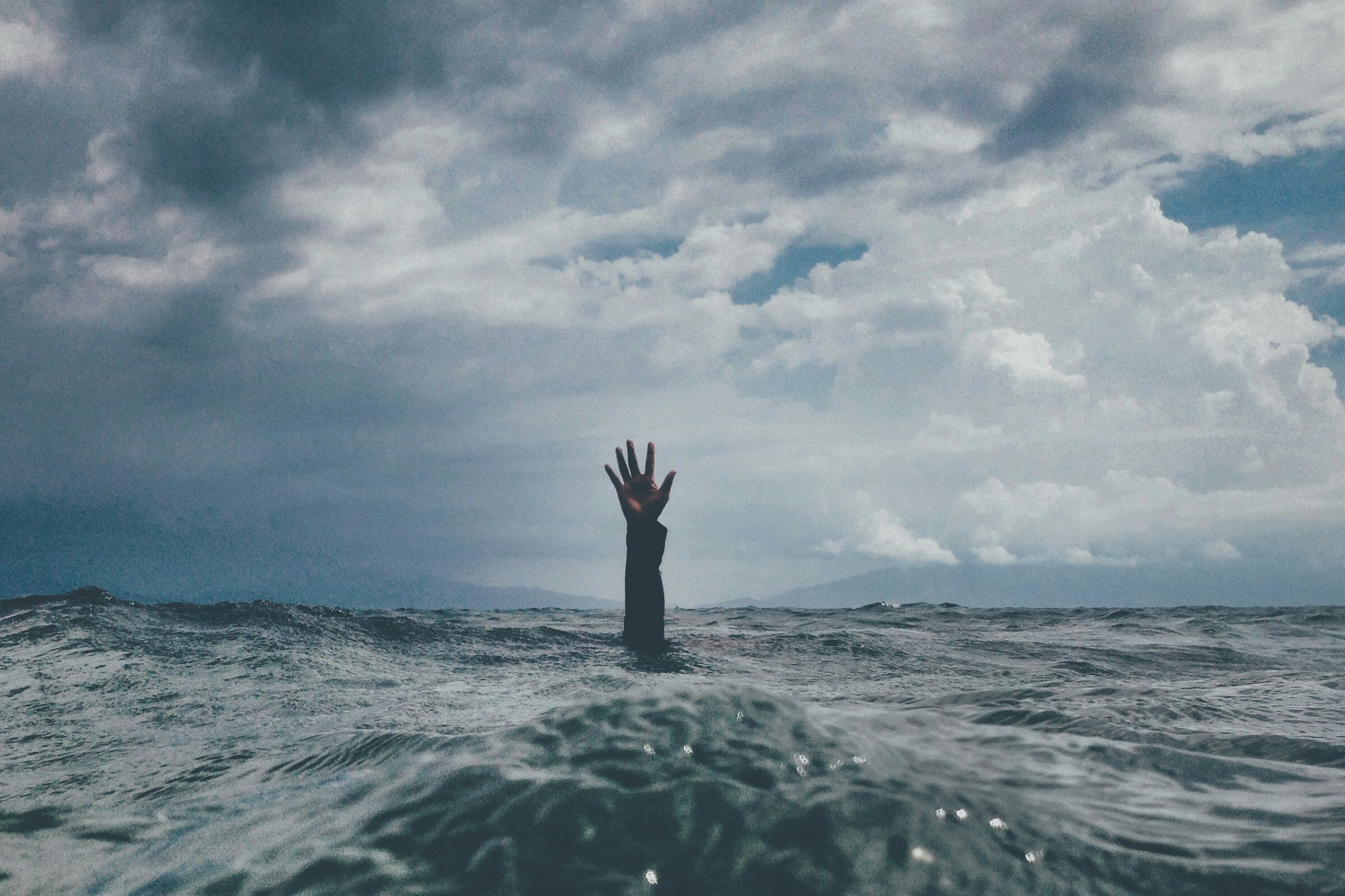 Een man die zijn hand opsteekt onder water om gered te worden